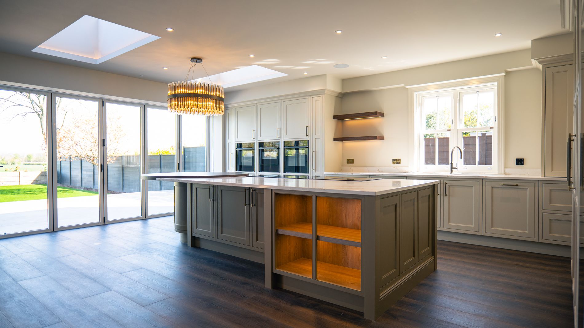 A kitchen with a large island and statement lighting, run by one Loxone system
